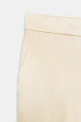 Pantalón de tiro medio de tejido satinado color beige, con bolsillos laterales, pernera recta y detalle de tejido superpuesto en las rodillas. Cierre frontal con cremallera, botón interior y ganchos metálicos ocultos.