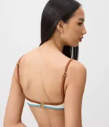 Top de bikini de media copa con aro, confeccionado en microfibra texturizada color blanco con detalles en celeste y tirantes finos marrones. Cuenta con un pequeño aplique metálico decorativo en el centro.