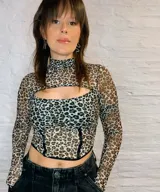Top tipo corset de microtul con estampado animal print. Presenta cuello alto, mangas largas con diseño de guante y una abertura frontal en el pecho. El área del busto se encuentra forrada para mayor cobertura, mientras que el resto de la prenda es traslúcida.