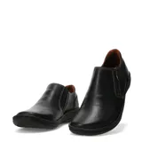 Zapatos casuales de cuero negro con cierre lateral metálico y costuras decorativas en contraste. Presentan una suela plana de goma con diseño ergonómico y forro interior en color marrón.