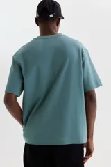 Remera de algodón color verde con cuello redondo ribeteado, mangas cortas y hombros caídos de corte holgado.