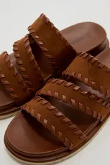 Sandalias planas color negro con tres tiras anchas adornadas con costuras cruzadas en el borde.