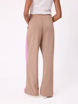 Babucha de corte holgado en color beige con paneles laterales en color fucsia y vivos blancos. Presenta cintura elástica y logo bordado en la parte superior.