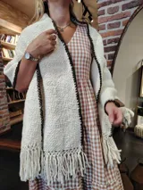 Chal tejido a mano en lana merino color crudo, con flecos y borde tejido en marrón oscuro. Diseño con textura de canasta.