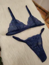 Conjunto de lencería compuesto por un corpiño triangular y una bombacha tipo colaless, ambos confeccionados en encaje de color azul profundo con detalles de malla.