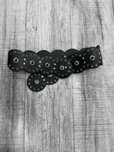 Cinturón ancho negro con apliques circulares de cuero sintético y ojales metálicos.