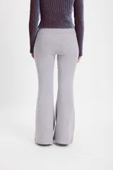 Pantalón de felpa gris con corte flare y terminación acampanada. Presenta una pretina elástica y detalle de costura vertical tipo alforza en el centro delantero.