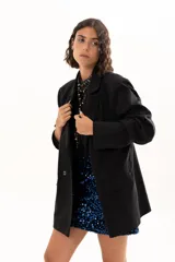 Blazer negro de corte oversize con solapas clásicas, cierre frontal de doble botonadura y bolsillos laterales con solapa.