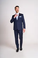 Ambo formal compuesto por saco de dos botones y pantalón de vestir a juego, en color azul marino. El saco presenta solapas clásicas, bolsillos con solapa y pañuelo de bolsillo a tono.