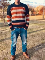 Sweater de lana merino a rayas horizontales en tonos azul marino, naranja y gris.