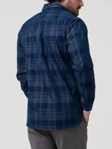 Camisa de cotelé azul de manga larga con estampado de cuadros escoceses, cuello camisero, cierre frontal con botones y dos bolsillos en el pecho.