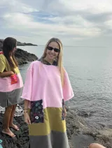 Poncho de toalla de manga corta con bloques de color rosa, verde oliva y gris. Tiene dos bolsillos frontales con estampado floral.