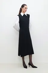 Vestido midi negro de tejido de punto, sin mangas, con cuello redondo y hombreras.