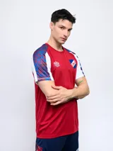 Remera de fútbol Umbro del Club Nacional de Football, modelo Pro Training Active. Diseño con estampado abstracto en blanco, rojo y azul, con mangas raglán azul marino y escudo del club en el pecho.