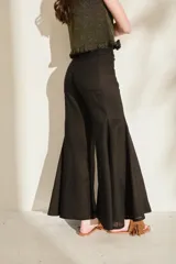 Pantalón negro de lino de tiro alto, con diseño ajustado en las caderas y perneras amplias y acampanadas con paneles insertados que generan mucho vuelo en el bajo.