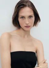 Vestido corto negro sin mangas, con escote palabra de honor, diseño evasé y cierre de cremallera en la parte posterior.