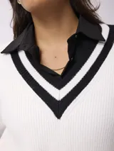Sweater de punto estilo preppy, color blanco con detalles de rayas negras en el escote en V, puños y ruedo. De corte holgado y manga larga.