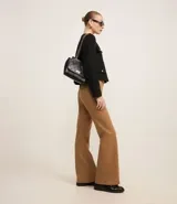 Pantalón de mujer modelo flare, confeccionado en punto roma color marrón, con cintura alta, bolsillos delanteros de solapa, bolsillos traseros embutidos y cierre delantero con cremallera.
