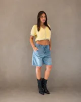 Bermuda de denim celeste con lavado suave, de calce relajado y tiro medio. Presenta diseño de cinco bolsillos y cierre frontal con botón y cremallera.