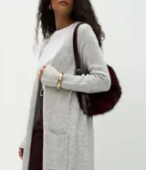 Cardigan largo de punto color gris, con diseño recto, cuello abierto sin cierre, mangas largas con puños acanalados y bolsillos frontales.