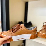 Championes acordonados de cuero color camel con suela blanca y detalles en marrón.