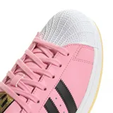 Championes adidas Superstar edición especial Messi, color rosado con las icónicas tres tiras laterales en negro. Presenta la puntera de goma clásica, logo de Messi grabado en el lateral y suela de goma color caramelo.