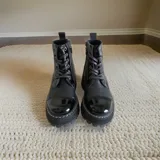 Borcego de cuero negro con cordones, suela de plataforma y detalles de arte pintado a mano en el talón.
