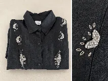 Camisa de lino negro con cuello clásico y cierre frontal de botones. Presenta detalles bordados a mano con cuentas plateadas y hilos en forma de motivos abstractos en la parte frontal.