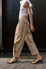 Pantalón de tiro bajo con pinzas delanteras, bolsillos frontales y bolsillos de plastrón con solapa en la parte trasera. Presenta una pernera ancha y bajo con botones a presión para ajuste.