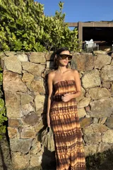 Vestido largo strapless, ajustado al cuerpo, con estampado batik en tonos marrones y naranjas.