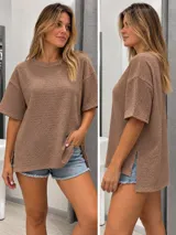 Blusa de manga corta color marrón con textura de bámbula, cuello redondo y aberturas laterales en el dobladillo más largo en la parte trasera.