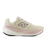 Championes de running New Balance modelo 1080v15, color beige con detalles en rosa pastel y logo lateral en gris. Presentan una parte superior de malla transpirable y una mediasuela con tecnología de amortiguación para un mayor retorno de energía.