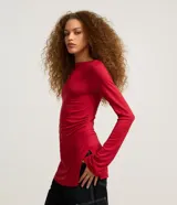 Blusa roja ajustada de manga larga, confeccionada en tejido rib, con cuello redondo y diseño largo con fruncidos laterales y aberturas en los costados.