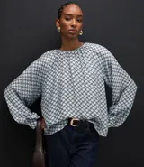 Blusa de mangas largas abullonadas con cuello redondo fruncido y diseño de estampa geométrica en tonos azul y blanco.