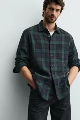 Camisa de corte regular fit confeccionada en tejido doble de algodón, con diseño de cuadros en tonos verde y azul marino. Presenta cuello solapa, manga larga con puño abotonado, bolsillo plastrón en el pecho y cierre frontal con botones.