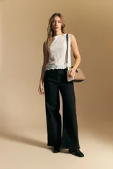 Top sin mangas de jacquard color negro, con cuello cerrado y silueta recta. Presenta una textura trabajada con relieve y una terminación suavemente ondulada en el ruedo.