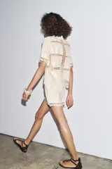 Blusa de algodón color crudo con detalle de bordados y crochet. Cuello redondo, manga corta y cierre frontal con botones.