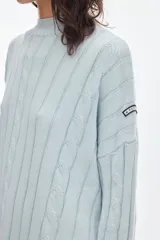 Buzo negro de tejido de ochos, con cuello redondo y diseño oversized de corte largo y amplio con tajos laterales.