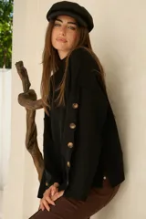 Sweater de bremer color negro con cuello alto, diseño holgado y mangas anchas con detalle de botones laterales.
