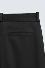 Pantalón chino de corte oversized confeccionado en tejido de algodón con estructura twill. Presenta bolsillos frontales, bolsillos traseros de vivo y cierre frontal con cremallera y gancho metálico oculto.