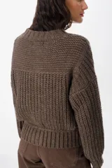 Saco de punto grueso color chocolate, con cuello redondo, cierre frontal con botones grandes y diseño de textura acanalada. Presenta un calce relajado y mangas largas con puños ajustados.