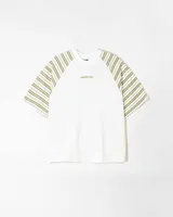 Remera unisex de jersey color blanco con mangas raglán a rayas horizontales en tonos verde oliva y blanco. Presenta un pequeño bordado en el pecho.
