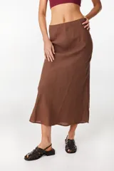 Falda larga marrón de corte sirena confeccionada en lino italiano, con diseño fluido al sesgo y pretina interior elástica.