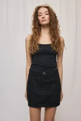 Falda de denim blanca de corte recto con bolsillos delanteros aplicados, costuras pespunteadas a contratono y cierre frontal con botón y cremallera.