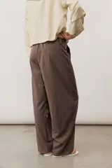 Pantalón de corte ancho y holgado, de color negro, con diseño estructurado y cinturón ajustable integrado en la cintura.