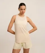 Musculosa deportiva Get Over de microfibra texturizada color marfil, con cuello redondo, tirantes anchos y bajo redondeado.