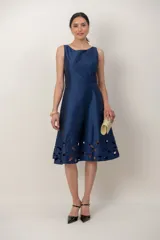 Vestido midi azul marino de tafeta, sin mangas, con escote recto y espalda en V. Presenta un detalle de bordado calado en el ruedo.