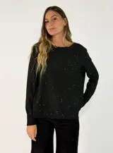 Sweater de punto negro con diseño de pequeñas motas brillantes distribuidas por toda la prenda. Presenta cuello redondo, mangas largas con puños ajustados y un corte ligeramente más largo en la parte trasera.
