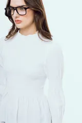 Camisa blanca de manga larga con diseño abullonado y puños fruncidos, detalle de nido de abeja en el frente y cuello alto con volados.