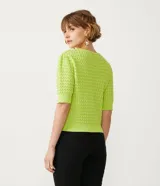Blusa de punto color verde lima, de manga corta y cuello redondo. Presenta un diseño con textura de relieve en todo el cuerpo y terminaciones acanaladas en cuello, puños y cintura.